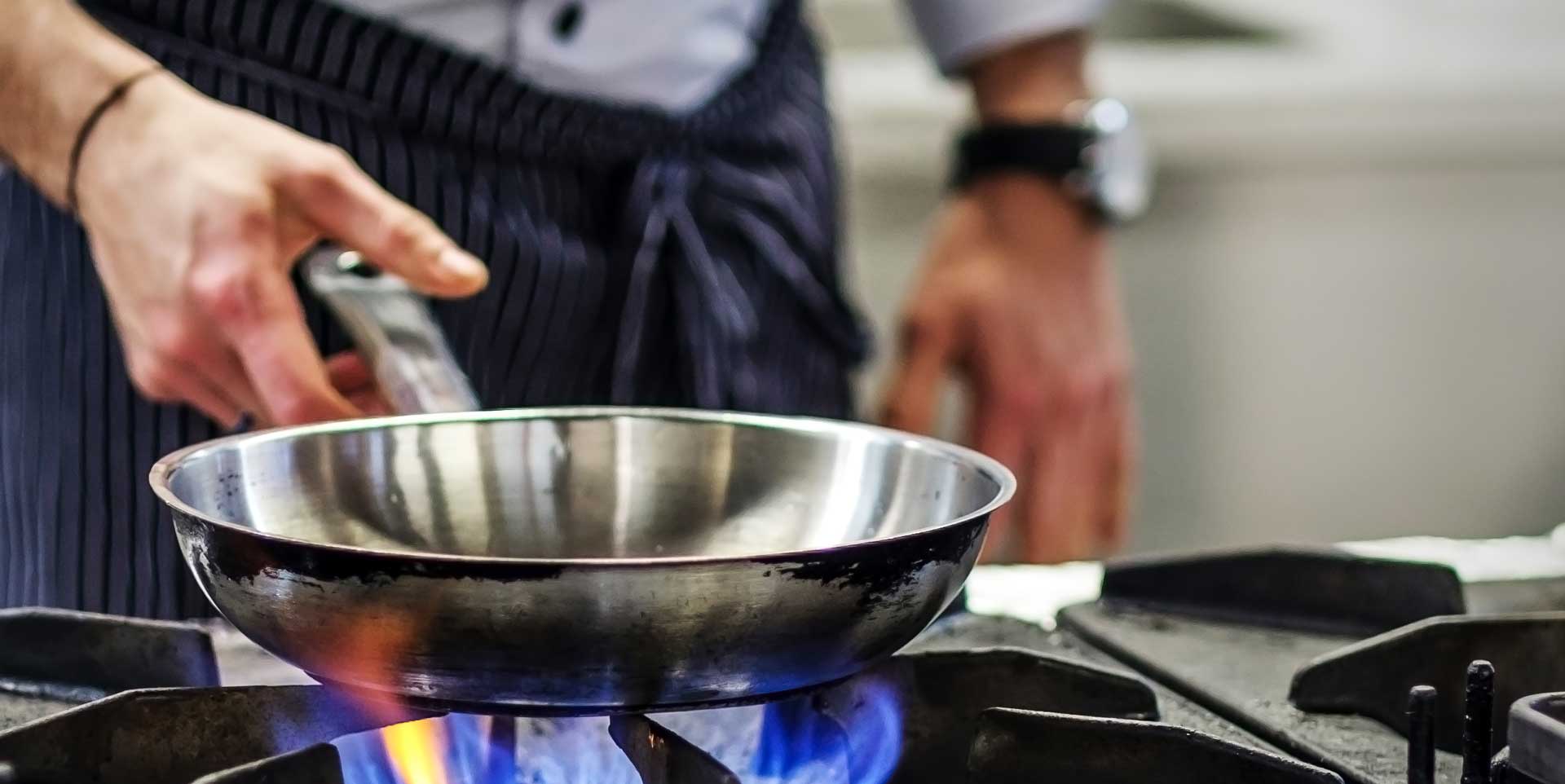Chef heating a stainless steel pan over an open gas flame: pan-roasting technique for Beverly Creek Farm's all-natural Ontario boneless lamb sirloin recipe