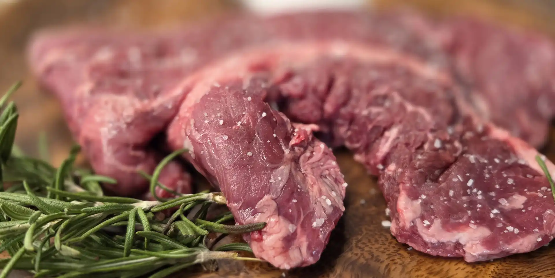 Meat Tender on a wooden chopping board with dressing and some salt crystals for flavour
